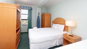 Et hotelværelse med en seng, et natbord, et skab og et vindue med gardiner.
