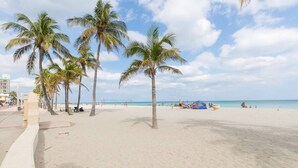 Une plage de sable avec des palmiers et un ciel dégagé.