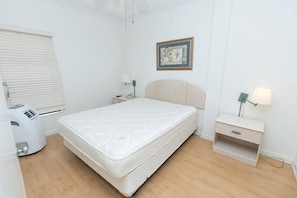 Quarto com cama, mesas de cabeceira, luminária, aquecedor e janela com persianas.