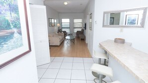 A spacious living area with a sofa, chairs, and a small table. There is a kitchen area with a counter and stools. - 805 PH 5 City View Penthouse Hollywood Beach (Hollywood)