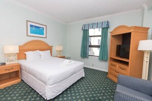 A hotel room with a bed, two bedside tables, a television on a wooden stand, a window with curtains, and a framed picture on the wall. - 638 Ocean View Hollywood (Hollywood)