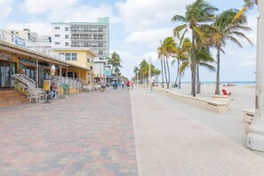 A beachfront promenade with palm trees, a beach, and buildings with shops. - 660 Ocean View Hollywood (Hollywood)