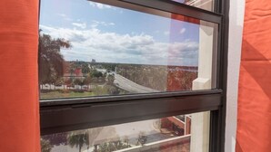 A window with a view of a highway and surrounding greenery. - 737 City View Studio on the Hollywood Beach Boardwalk (Hollywood)