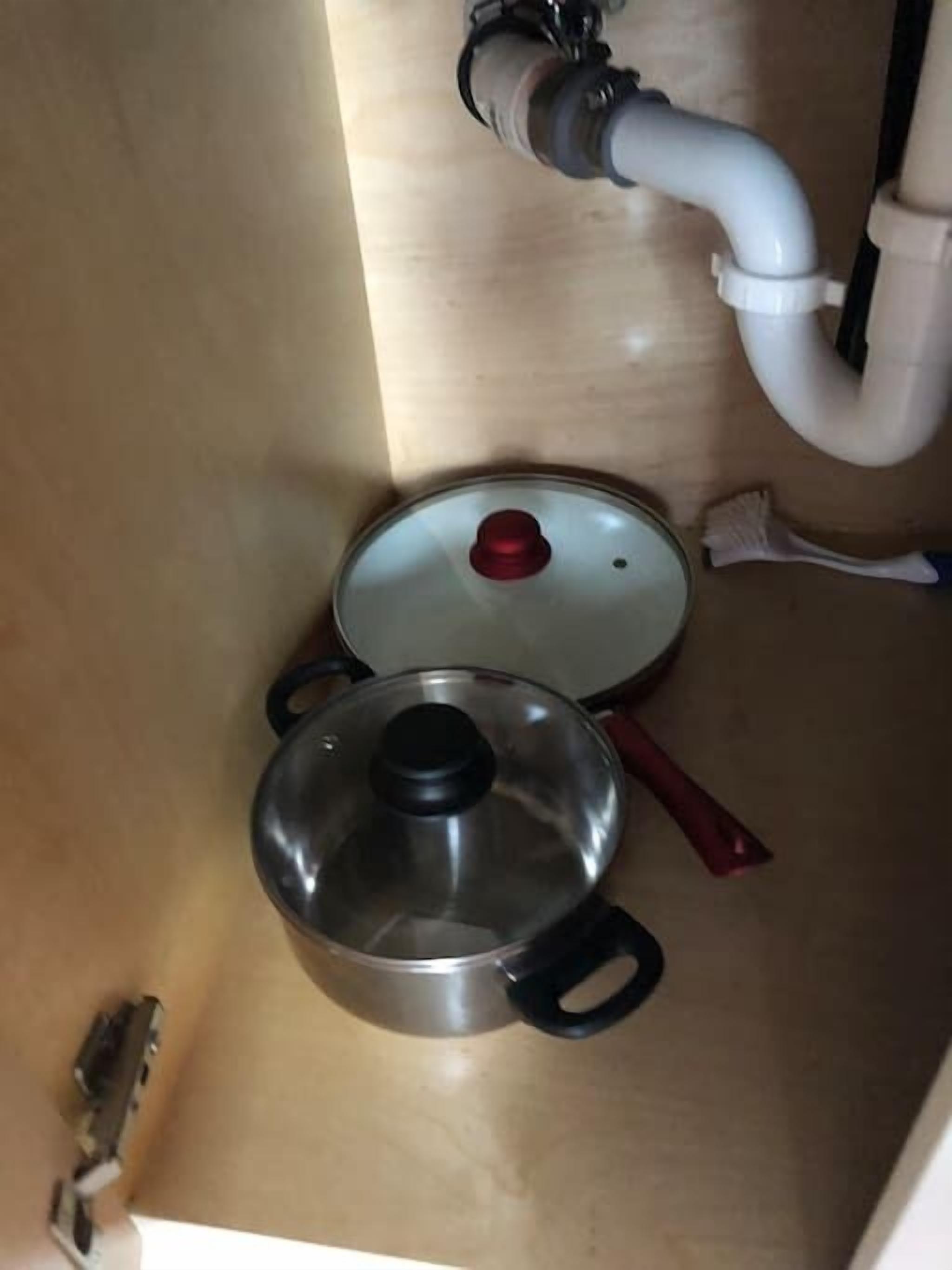 Um armário de cozinha com uma panela e uma frigideira.