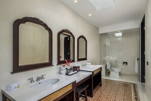 Ein modernes Badezimmer mit zwei Waschbecken, großen Spiegeln und einer Duschkabine.