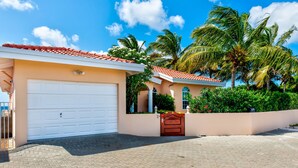 A two-story house with a white garage door, a red-tiled roof, and a small front porch. - Oceanfront Villa, Direct Ocean Access, Private Pool (Kralendijk)
