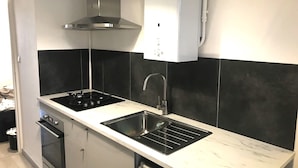 Eine moderne Küche mit zwei schwarzen Kochfeldern, einem Edelstahl-Spülbecken und einem eingebauten Ofen.