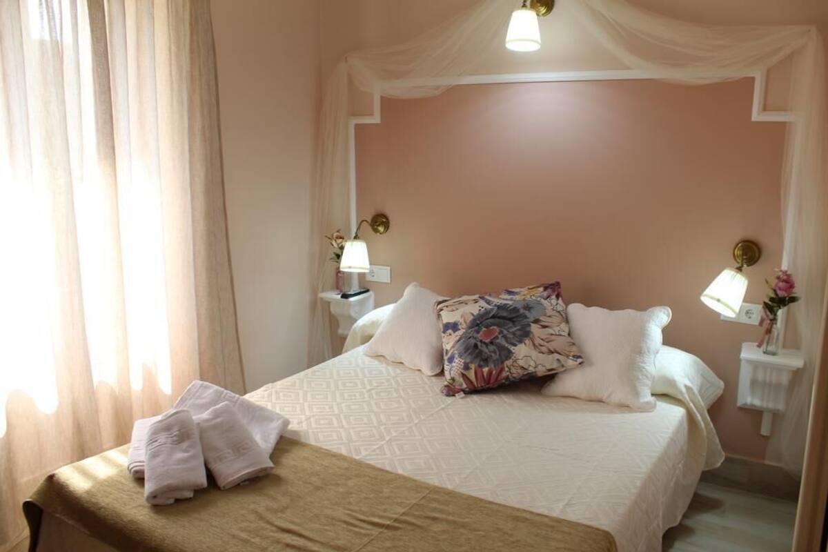 A neatly made bed with a patterned pillow, a bedside lamp, and a folded towel on a bedside table.