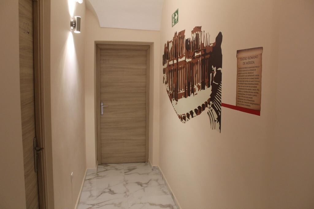 Un passadís amb una porta de fusta, una làmpada penjada a la paret i un cartell de teatre.