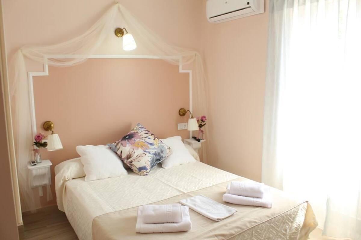 A neatly made bed with a canopy, white pillows, and folded towels on the bed.