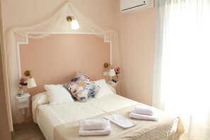 Ein ordentlich bezogenes Bett mit Baldachin, weißen Kissen und gefalteten Handtüchern.