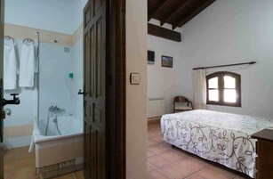 Un dormitorio con cama, ventana y baño con bañera y toallero.