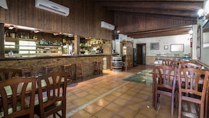 Un área de bar con paredes de madera, una barra de piedra y varias sillas de madera.