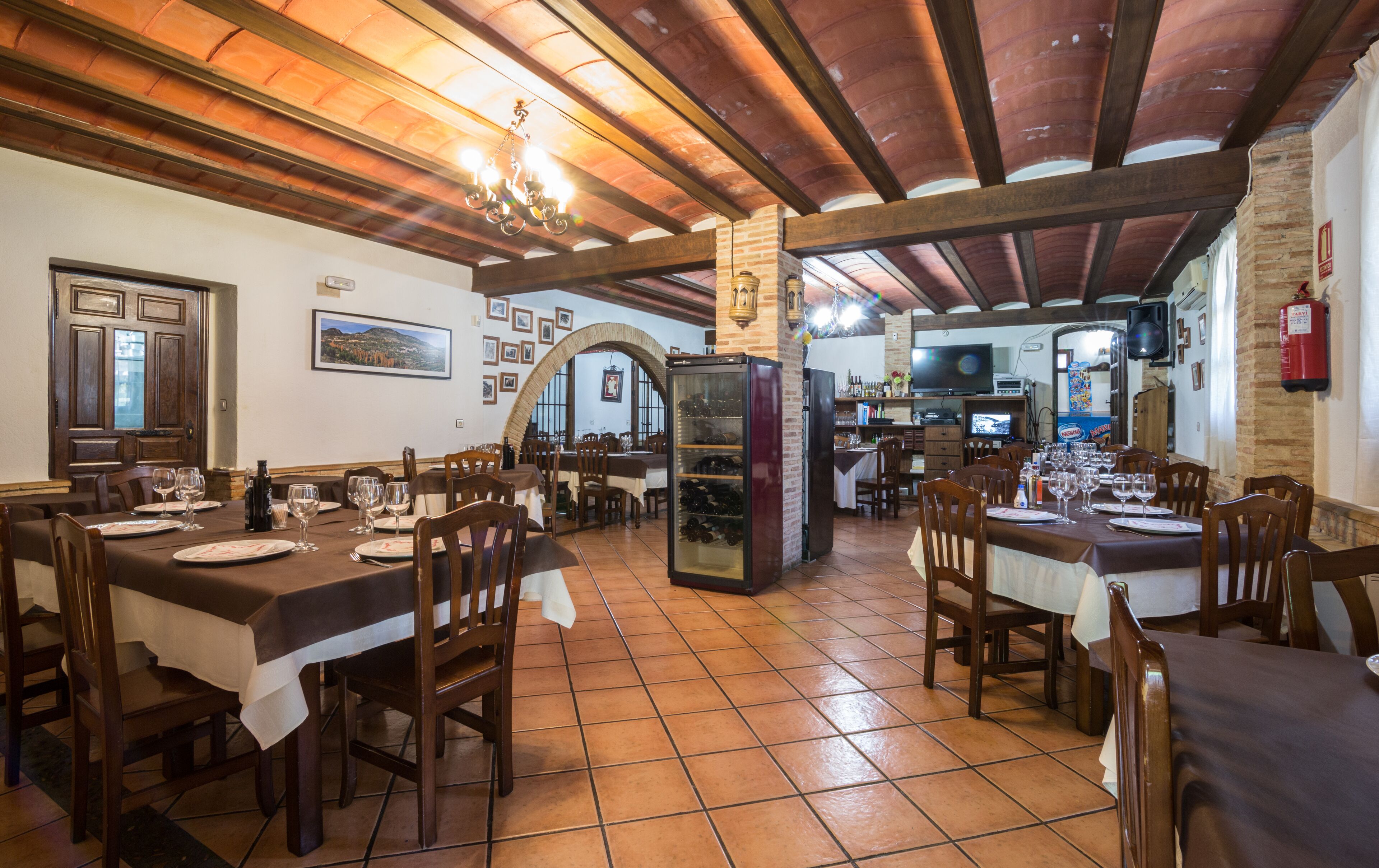 A restaurant with wooden tables and chairs, a tiled floor, and a brick wall.