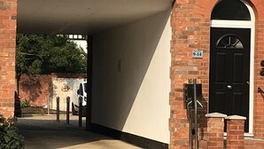 Een bakstenen gebouw met een overdekte ingang en een zwarte deur waarop ‘9-14’ staat.