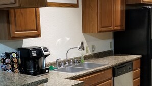 A kitchen with wooden cabinets, a black refrigerator, a coffee maker, and a patterned backsplash.