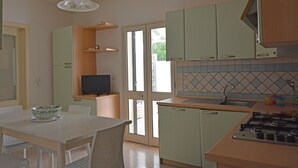 Een kleine keuken met een eethoek, een televisie en een gasfornuis.