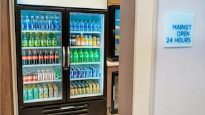 A vending machine with a variety of beverages and snacks, and a sign indicating the market is open 24 hours.
