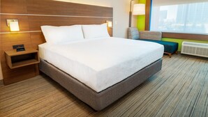 Een hotelkamer met een groot bed, nachtkastjes, een stoel, een raam met uitzicht en een wandlamp.