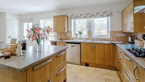 A modern kitchen with wooden cabinets, a granite countertop, and a window with a view of trees. - 3 bedroom accommodation in Hathersage (Hathersage)