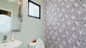 Een badkamer met een wit wastafel, toilet en raam.