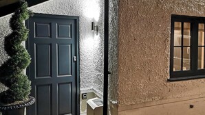 A dark door with a textured wall and a window with multiple panes.