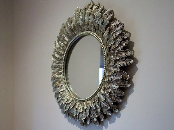 A wall-mounted mirror with an ornate, leaf-like frame. - The White House Studio (Worthing)