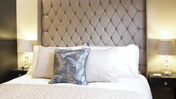 A neatly made bed with a tufted headboard, two bedside lamps, and a patterned pillow.