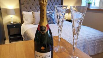 En flaska Bollinger-champagne och två champagneglas på ett träbord i ett hotellrum.