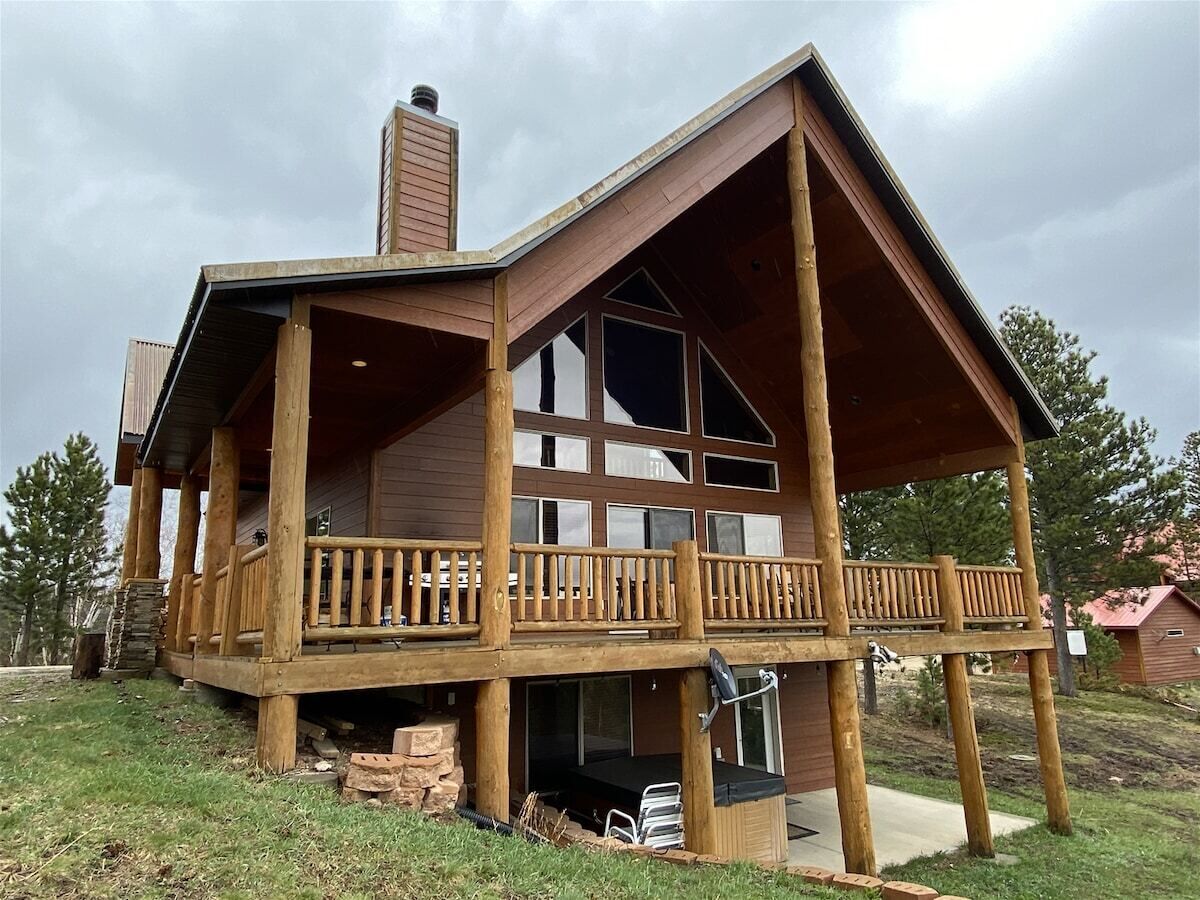 A wooden cabin with a balcony, large windows, and a chimney.