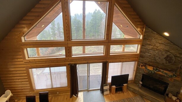 A log cabin with a large central skylight, stone fireplace, and a cozy seating area.