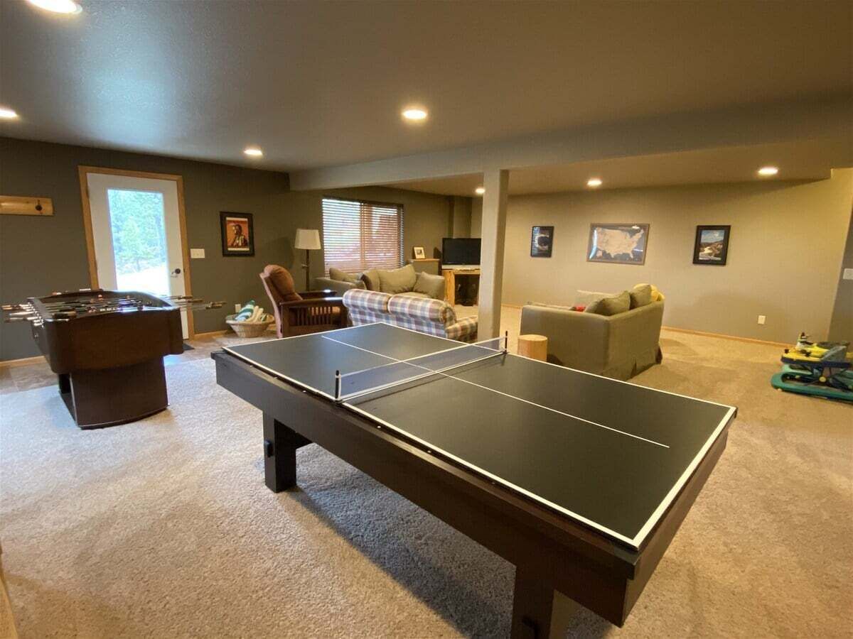 Una habitación con mesa de ping pong, mesa de fútbolín y sofá.