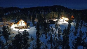 A cabin with a porch, surrounded by snow and trees.