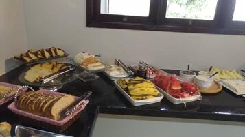 Un bufé con diversos alimentos, como pan, plátanos y un postre.