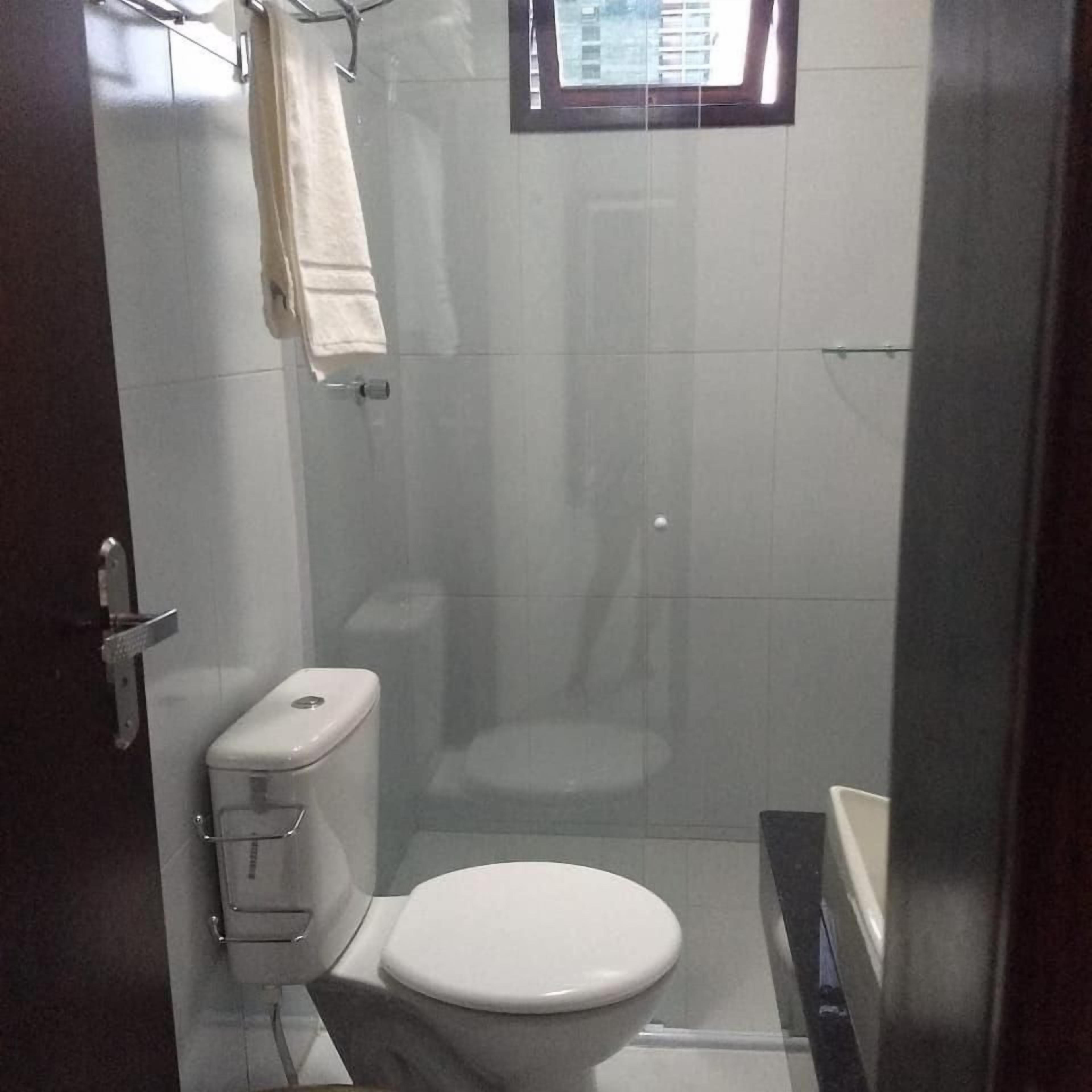 Un baño pequeño y cerrado con inodoro, cabina de ducha y bañera.