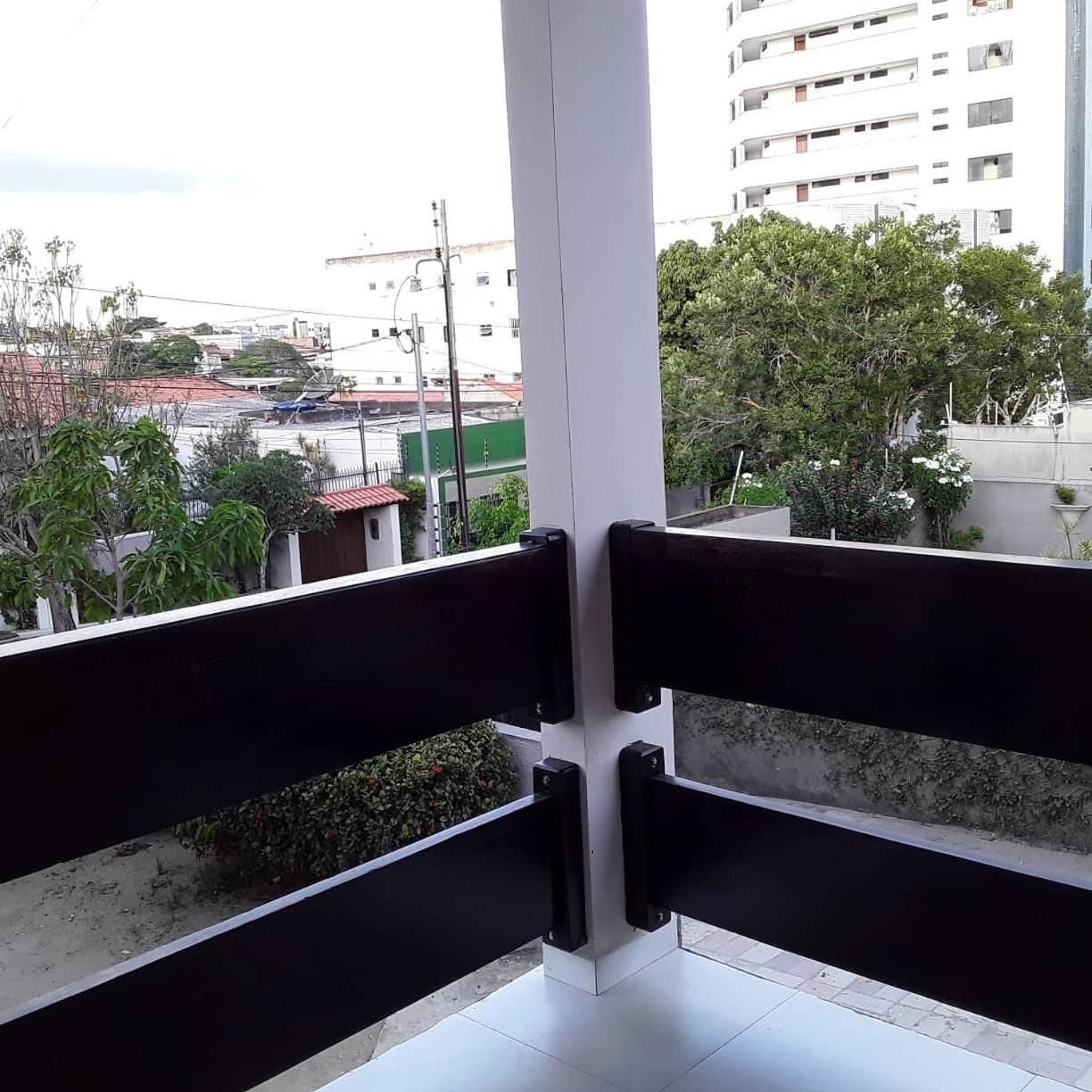 A balcony with a view of a cityscape, including buildings and trees.