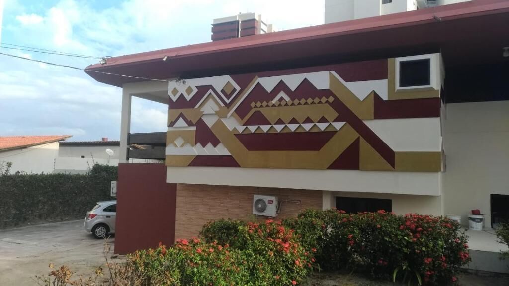 A building with a patterned facade, a parked car, and a small window.