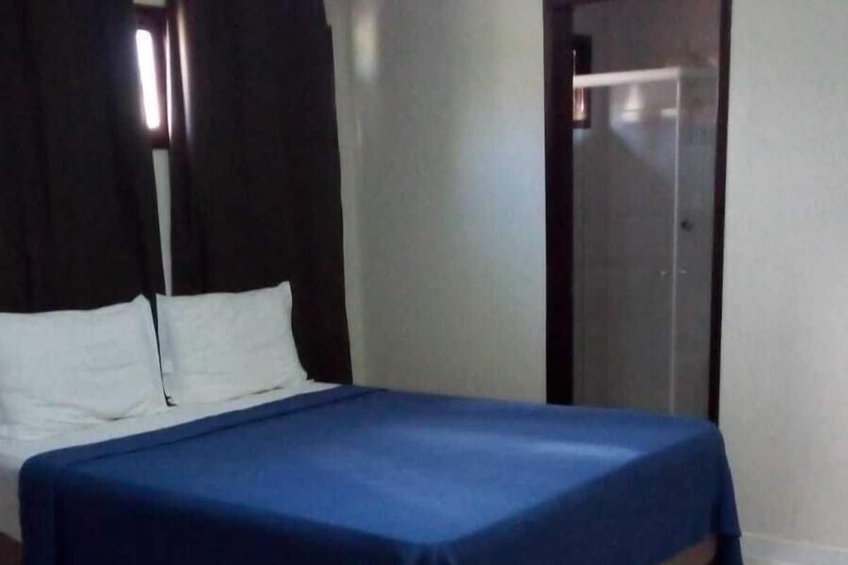 A bedroom with two beds, white walls, and a tiled floor.