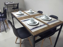 Comedor con una mesa rectangular dispuesta para cuatro personas, rodeada de sillas negras.