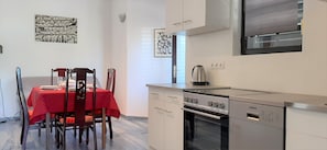 A compact kitchen with a red table set for dining, a Koncar oven, and a refrigerator.
