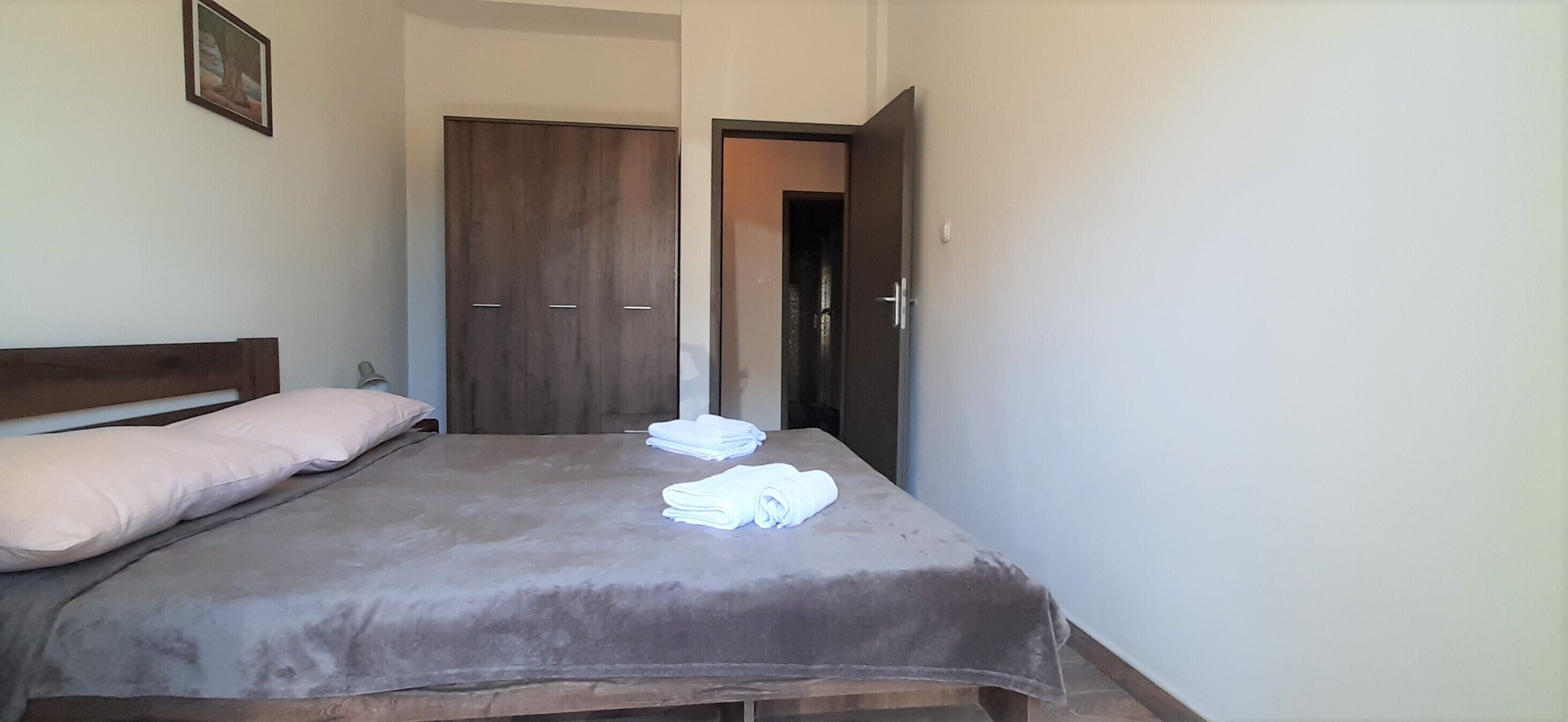 Ein Schlafzimmer mit einem Bett, einem Holzschrank und einer Tür zu einem weiteren Raum.