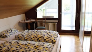 Une chambre avec deux lits, une fenêtre, un radiateur et une petite table avec des chaises.