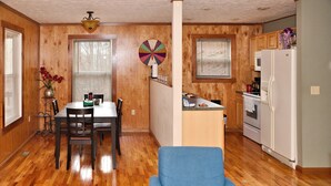 A compact kitchen with wooden cabinets, a white refrigerator, and a dining area with a table and chairs. - Morehead Cabin on the lake (Morehead)