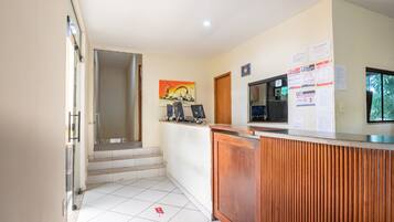 Zona de recepción con mostrador de madera, una computadora y un cuadro en la pared.