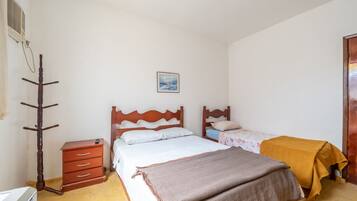 Ein Schlafzimmer mit zwei Betten, einem Holzschrank, einem Kleiderständer und einem Bild an der Wand.