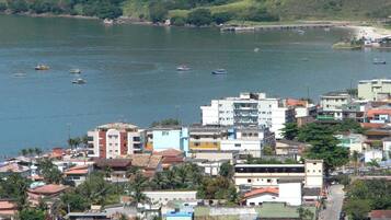 A coastal town with buildings along the waterfront, boats in the water, and a hilly background.