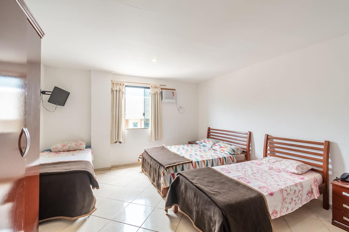 A hotel room with two beds, a TV, a window with curtains, and a bedside table.
