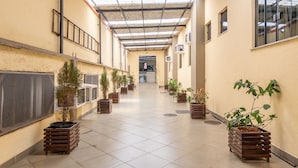 A corridor with tiled flooring, potted plants, and air conditioning units on the walls. - OYO Residencial Muriqui Apart Hotel, Mangaratiba (Mangaratiba)