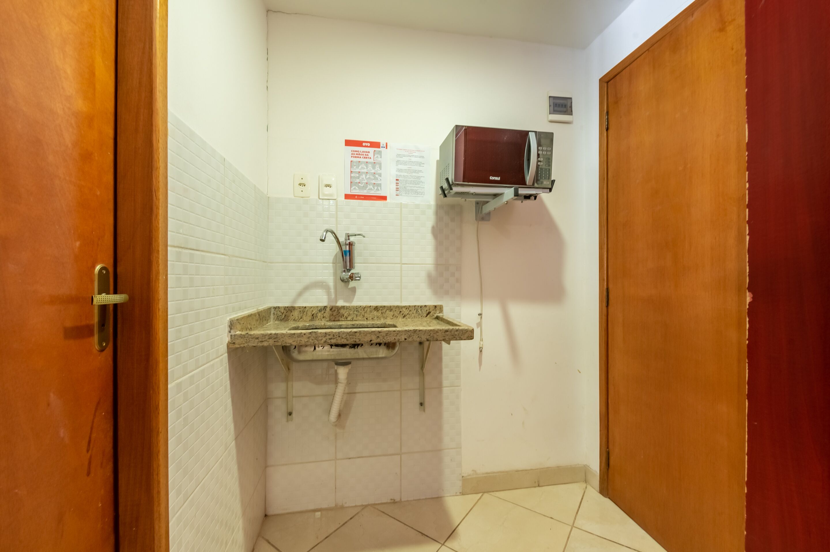 A bathroom with a sink, a mirror, a towel rack, and a microwave.