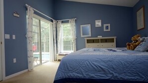 Quarto com cama grande, penteadeira e um urso de pelúcia.